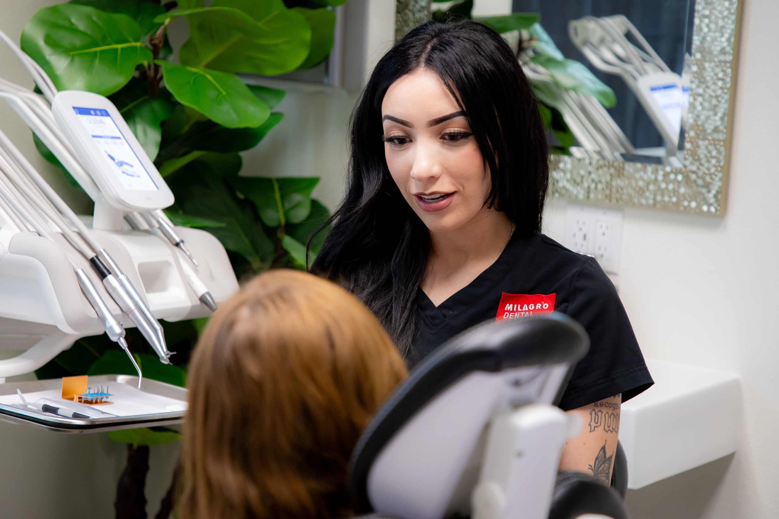A friendly dental team member at Milagro Dental in Santa Fe, New Mexico, consults with a patient in a modern treatment room with professional equipment.