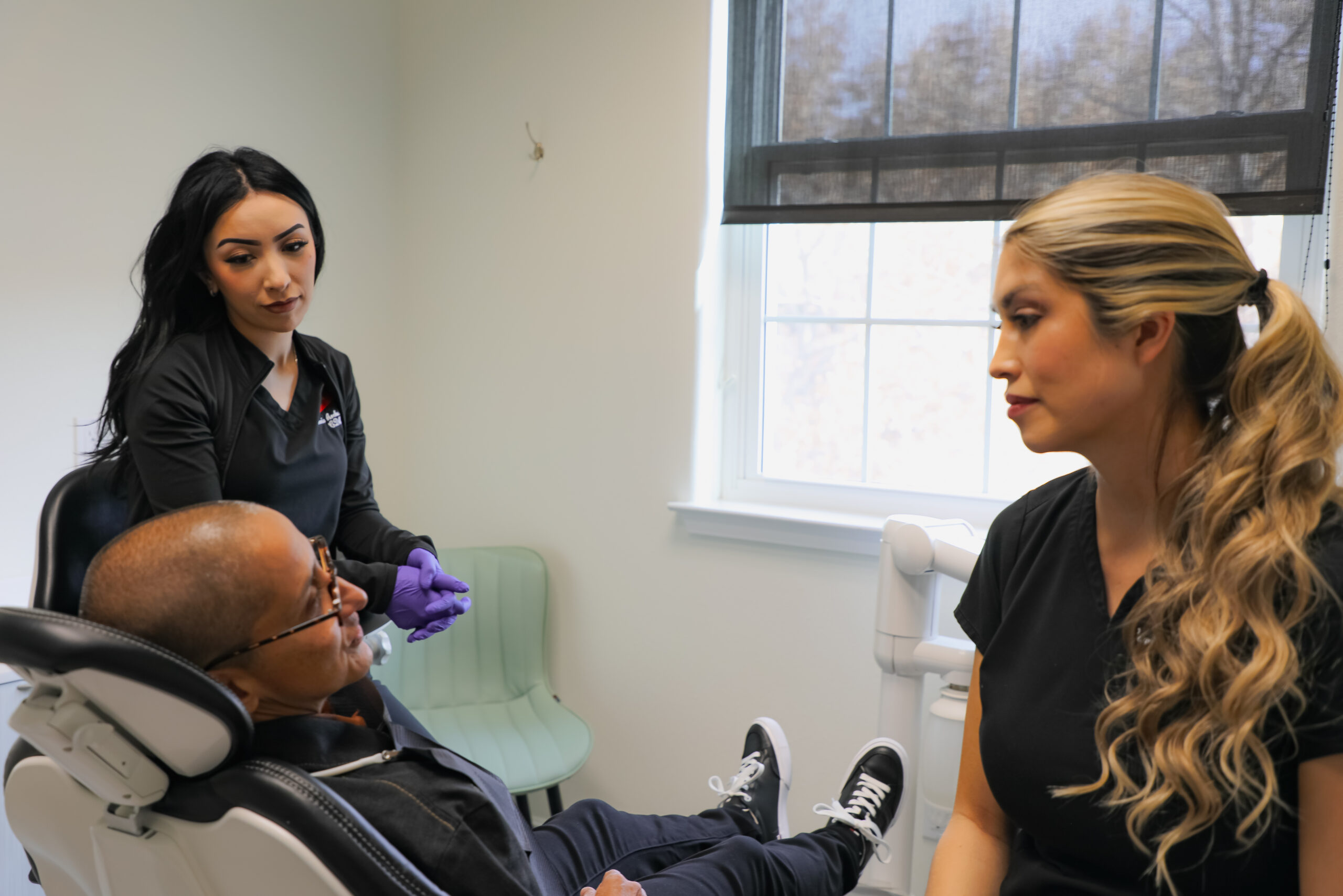 A team of dental professionals at Milagro Dental in Santa Fe, New Mexico, provides personalized care and consultation to a patient in a modern treatment room.